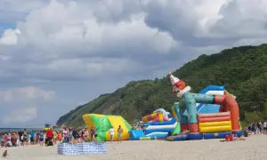 Kolorowe dmuchańce na plaży w Międzyzdrojach to świetne atrakcje dla dzieci. Wesoły klaun zaprasza do zabawy.