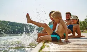 Rodzina pluska się w jeziorze, tworząc fajne miejsce na wakacje z dzieckiem w Polsce. Radość i beztroska na drewnianym pomoście.