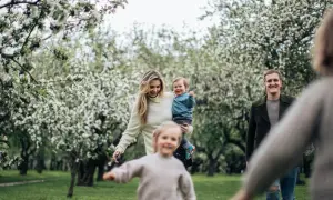 Radosna majówka z dziećmi w kwitnącym sadzie. Rodzina cieszy się wiosennym dniem wśród drzew.