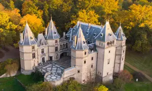 Malowniczy zamek z wieżyczkami, otoczony jesiennym lasem, zaprasza do zwiedzania. Idealne miejsce na jesienną wycieczkę po zamkach.