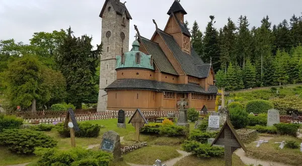 Drewniana świątynia Wang w Karkonoszach, otoczona cmentarzem i lasem.