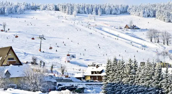Stok narciarski w Karkonoszach, idealne miejsce na ferie zimowe 2026 dolnośląskie. Narciarze szusują po ośnieżonych zboczach, a kolejki linowe wwożą ich na szczyt.