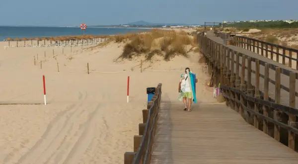 Spacerem po plaży, gdzie atrakcje grzybowo czekają na odkrycie. Drewniana kładka prowadzi do morza, a piasek lśni w słońcu.