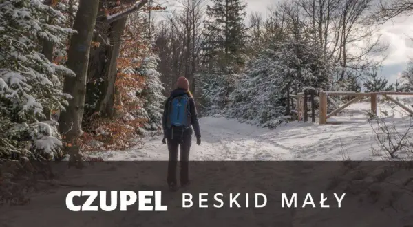 Kobieta z plecakiem idzie zimowym szlakiem w Beskidzie Małym. To czupel najładniejszy szlak, pokryty śniegiem.