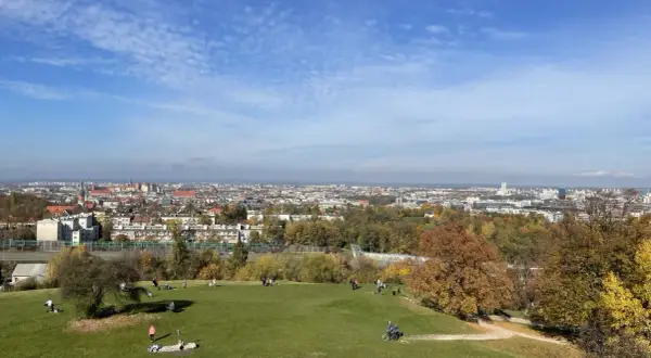 Jesień na Kopcu Kraka. Ludzie odpoczywają na zielonej trawie, w tle rozciąga się panorama Krakowa.