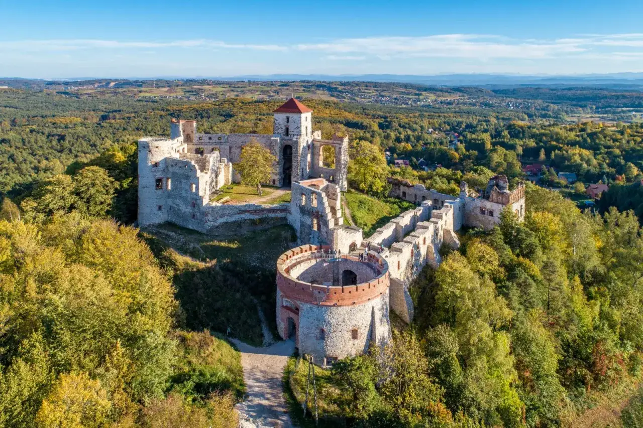 Zamek Tenczyn w jesiennej odsłonie, zapraszający do zwiedzania. Ruiny majestatycznie górują nad lasami, oferując niezapomniane widoki.