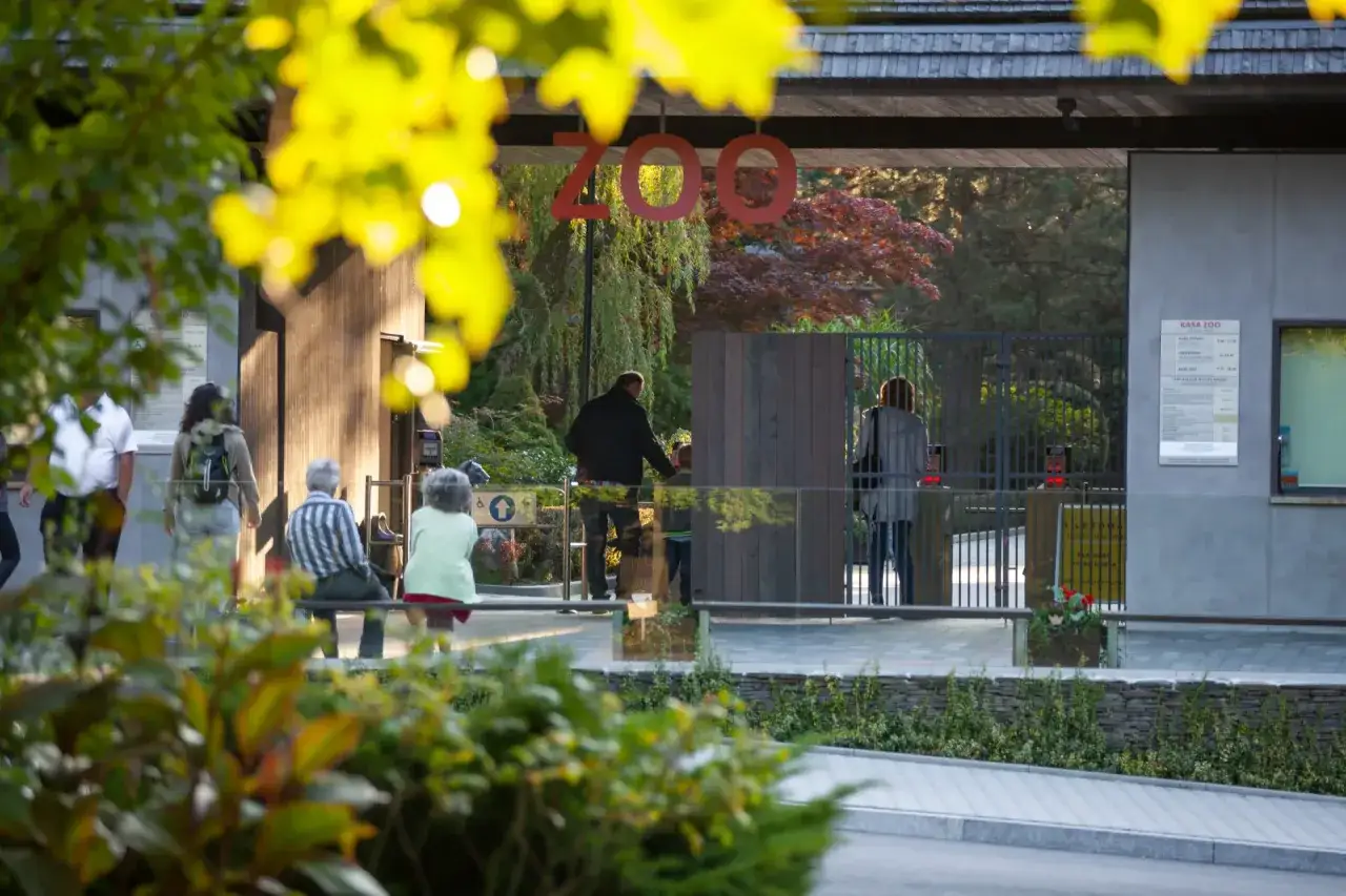 Wejście do największego zoo w Polsce. Ludzie wchodzą przez bramki, a nad nimi wisi napis 